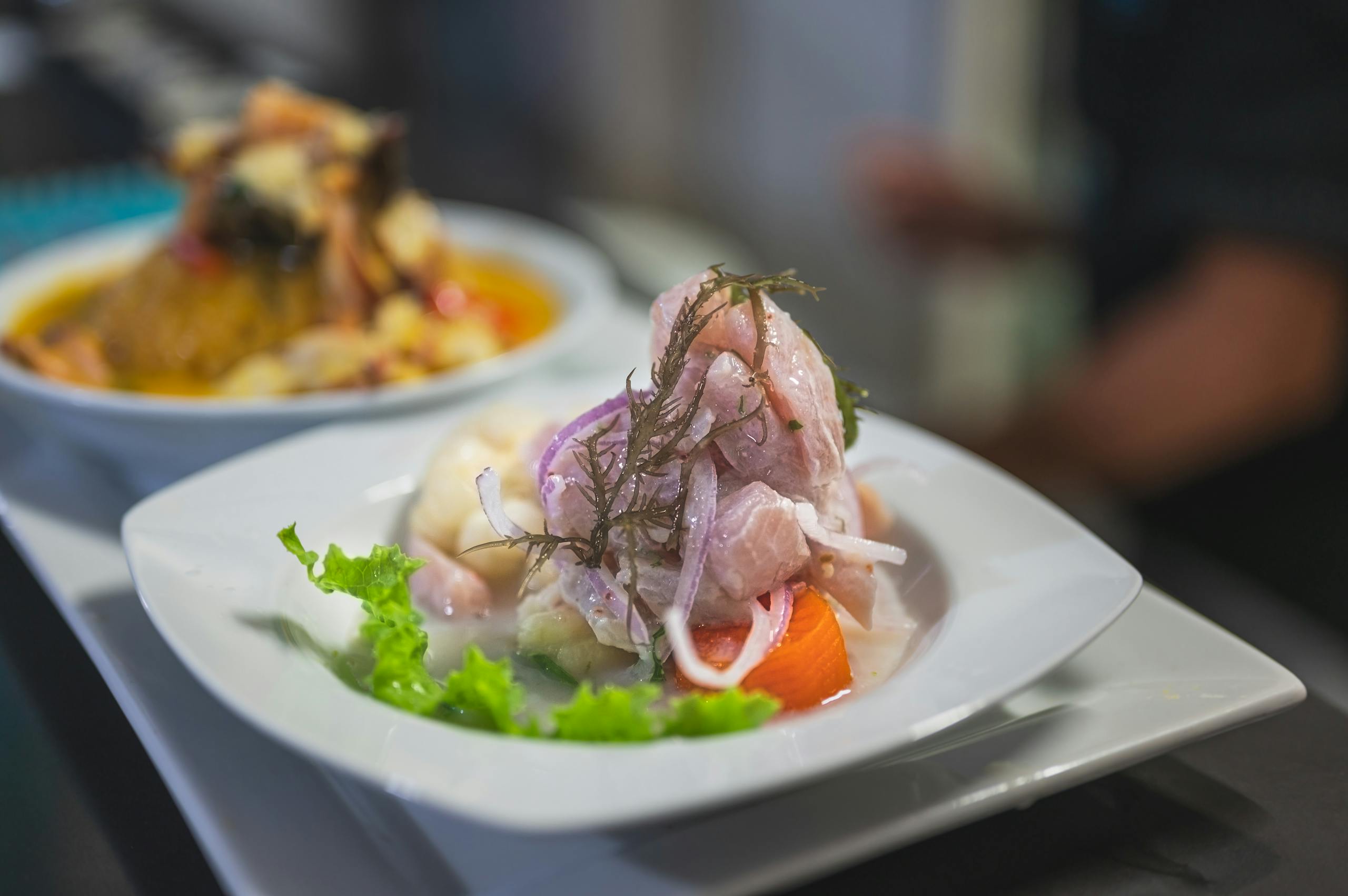 A vibrant dish of ceviche served on a white plate with colorful garnishes, offering fresh flavors.