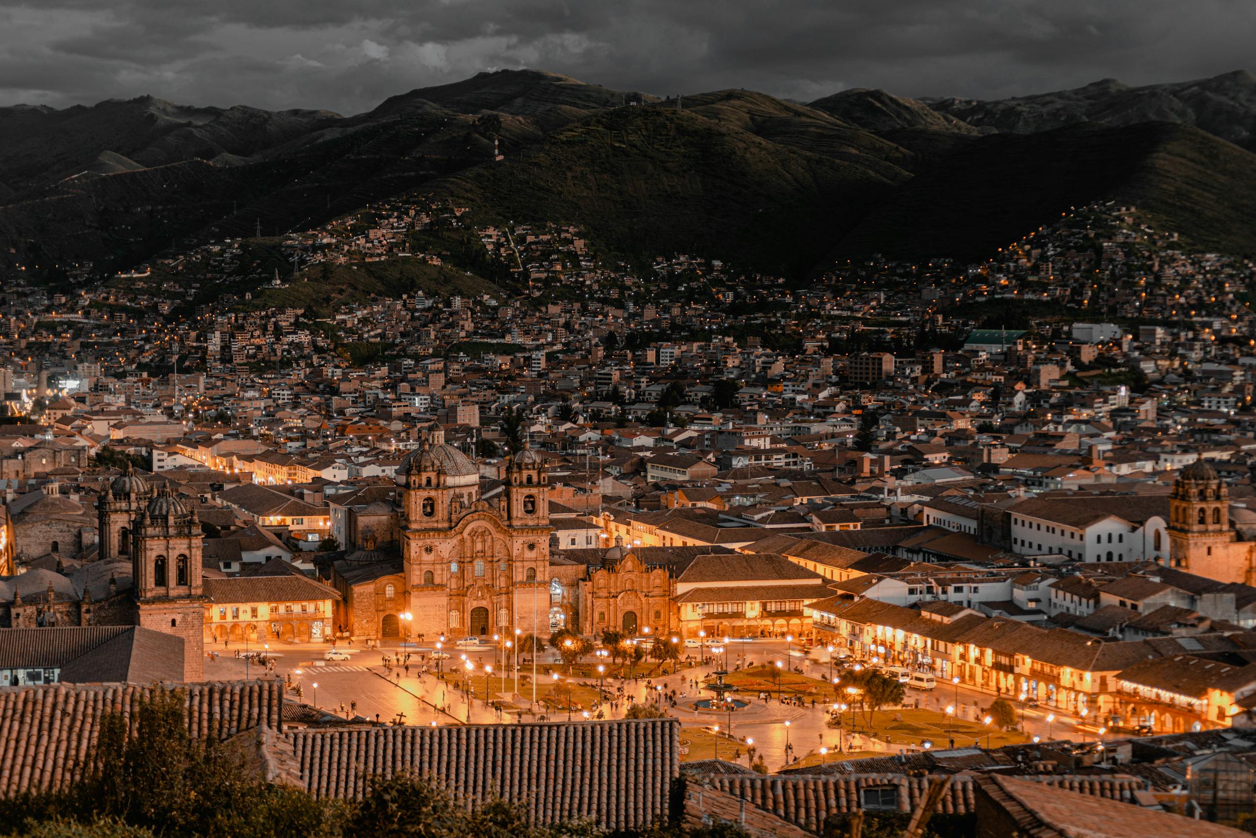 Aerial view of Cusco, Peru at twilight showcasing illuminated buildings and historic architecture.