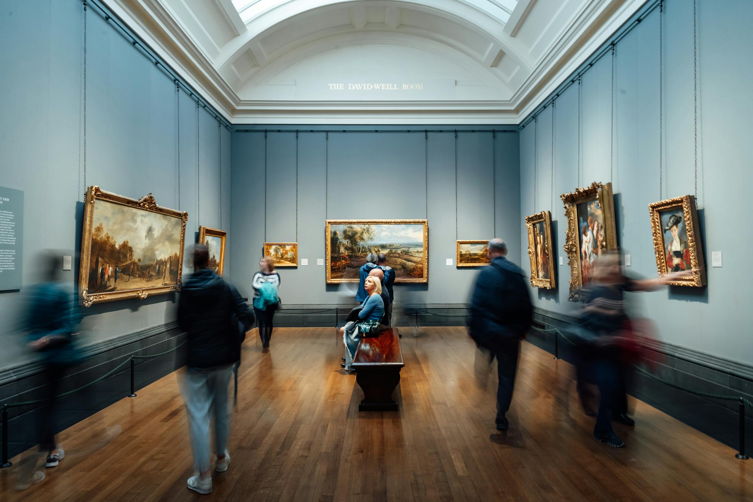 Art lovers admiring paintings in a gallery in England, showcasing culture and history.