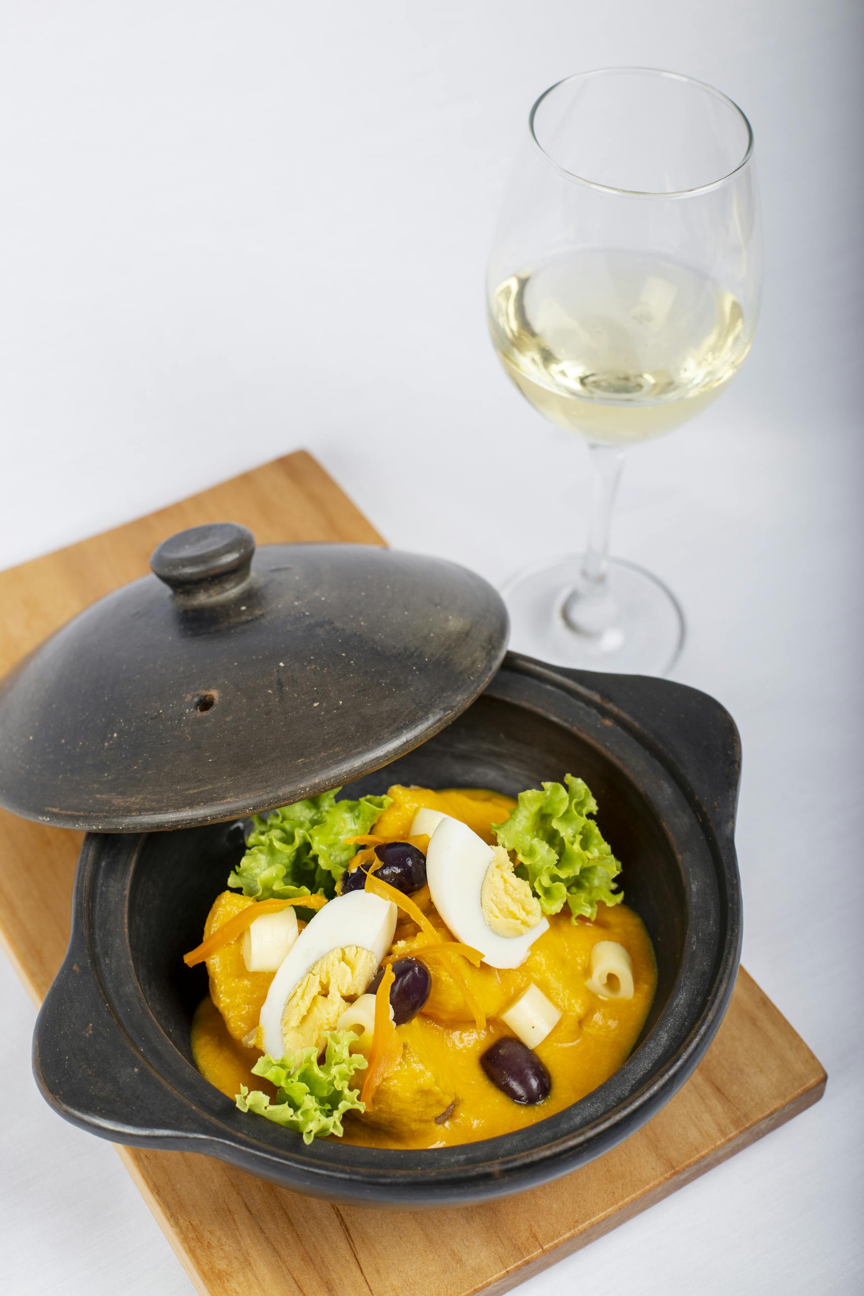 Delicious gourmet dish with boiled eggs served alongside a glass of white wine on a wooden board.