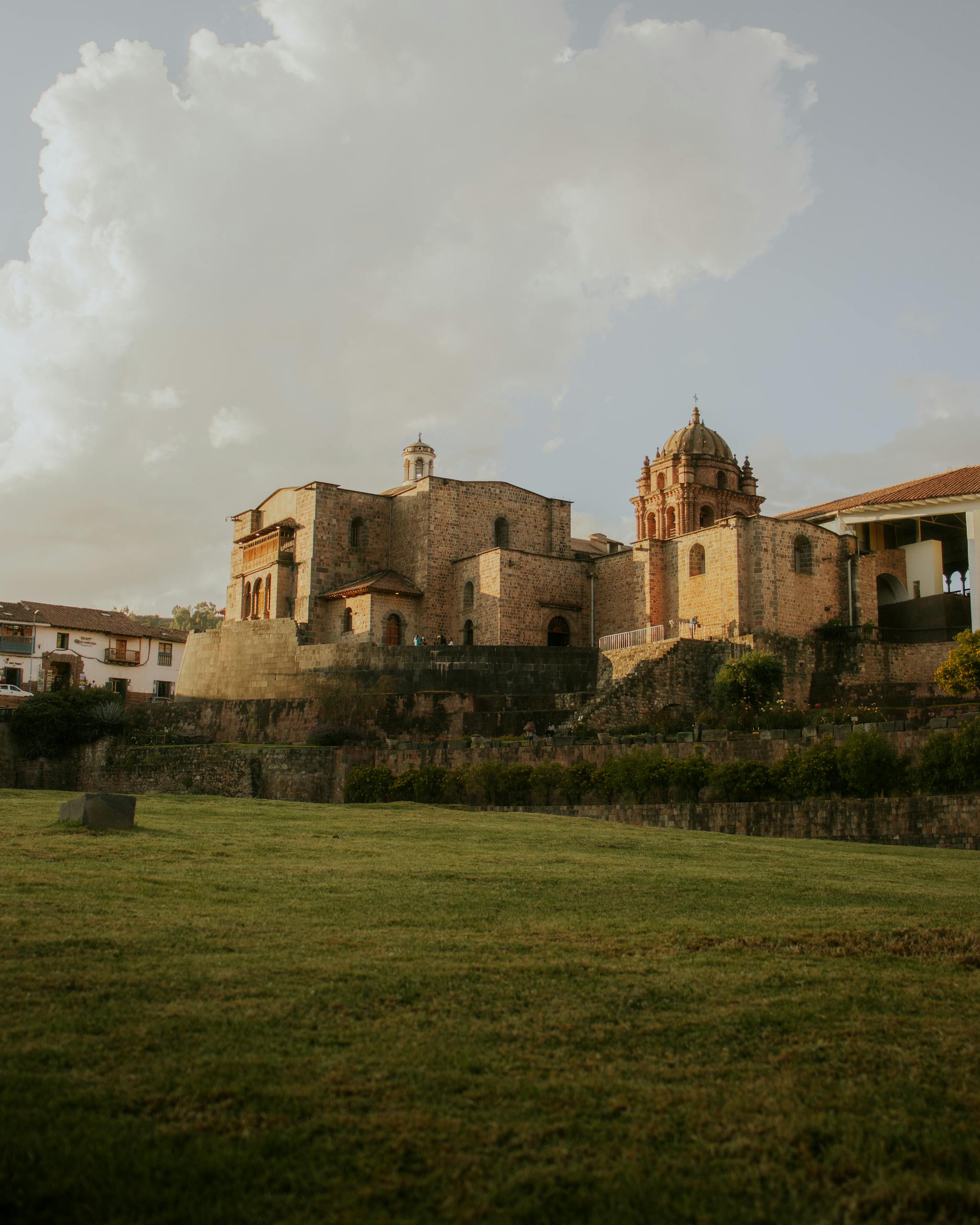 Scenic view of the Convent of Santo Domingo in Cusco, Peru, featuring historic architecture and a grassy foreground.